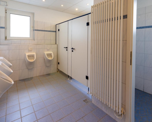 Herren-Sanitärbereich mit Toiletten und zwei Duschen