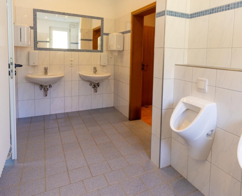 Herren-Sanitärbereich mit Toiletten und zwei Duschen